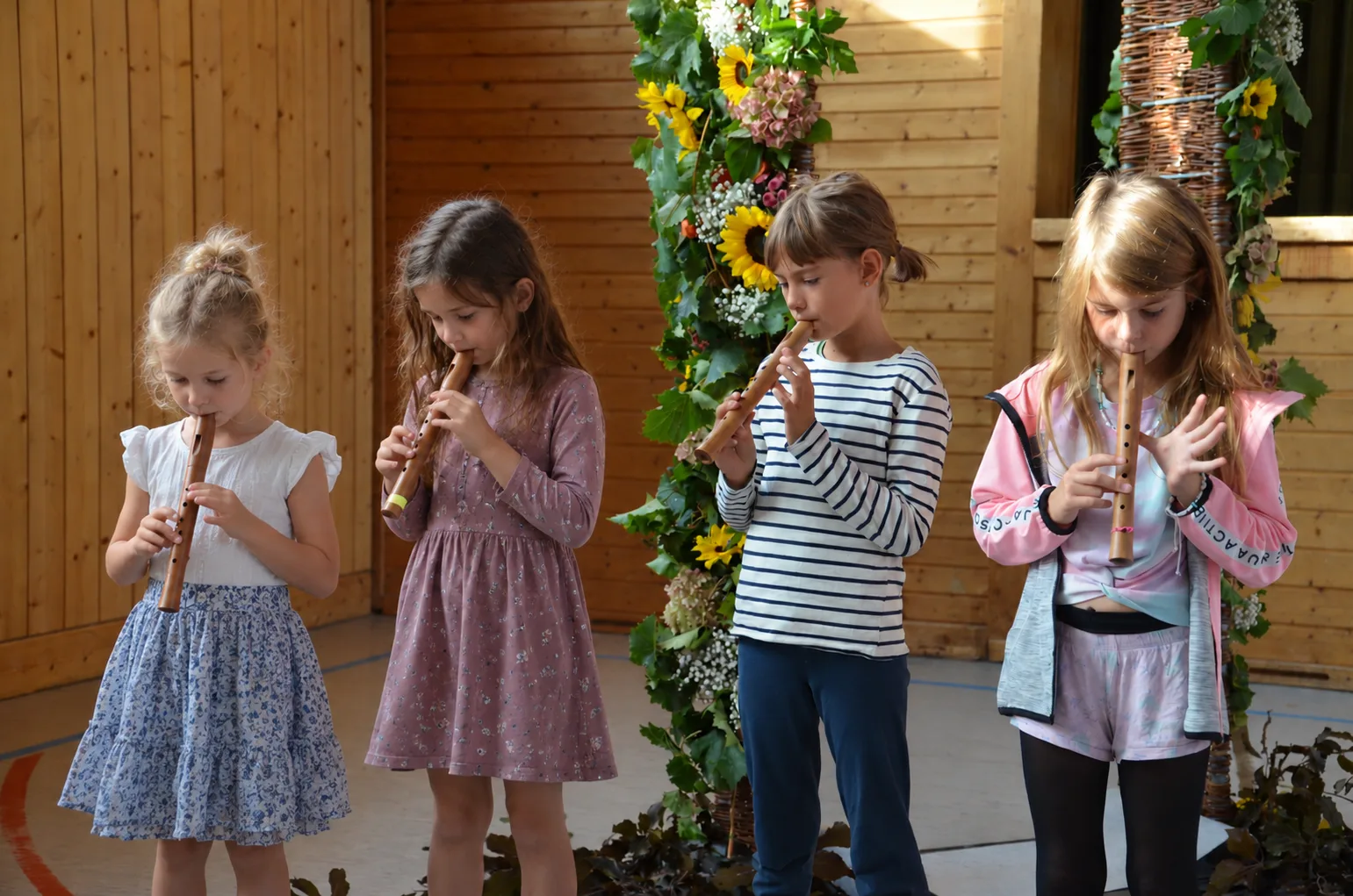 Kinder musizieren gemeinsam vor einer Holzkulisse